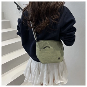 Detailed view of light green nylon crossbody bag with adjustable strap and silver zippers
