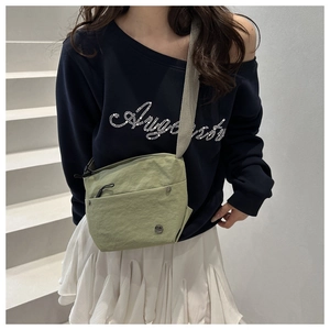 Detail of light green nylon crossbody bag with wide strap and front zipper pocket