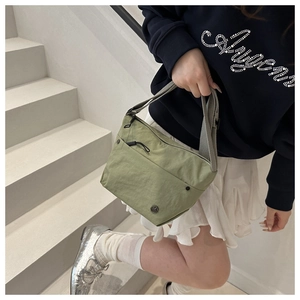 Close-up of light green nylon crossbody bag featuring waterproof fabric and grey strap