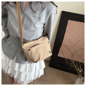Detail view of khaki nylon crossbody bag showing natural wrinkled texture and zipper