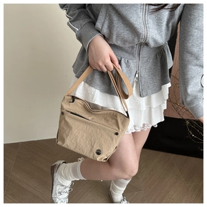 Close-up of minimalist nylon crossbody bag with front zipper and round metal logo