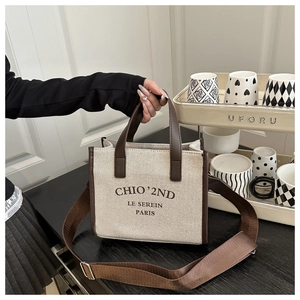 Detail of a chic canvas tote bag featuring brown leather trim and stylish logo printing