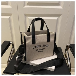 Detail of canvas tote bag with black leather handles and adjustable nylon shoulder strap