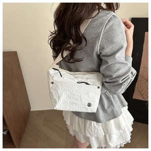 Detail of white wrinkled fabric crossbody bag with wide strap on casual model outfit