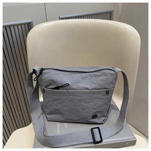Detailed view of light grey pleated puff crossbody bag with front zipper and logo