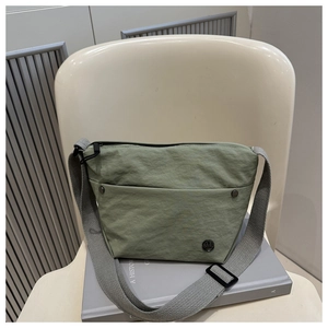 Detail of light green wrinkled nylon crossbody bag with wide strap and logo plaque