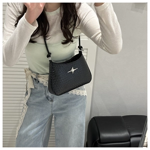 Détail de la texture crocodile et du fermoir étoile argenté du sac sous le bras noir