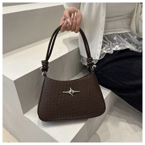 Detail of dark brown crocodile embossed shoulder bag with silver cross star emblem