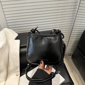 Glossy black patent leather crossbody bucket bag with adjustable knot shoulder strap