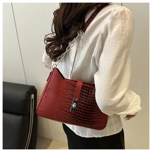 Detail of red crocodile embossed tote bag with silver chain strap and metal lock buckle