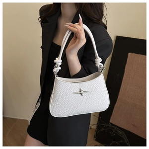 Close-up of white woven shoulder bag with silver star emblem and knot handle detail