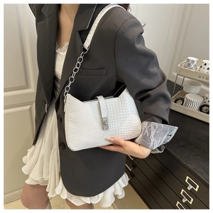 Detail of white crocodile pattern shoulder bag with silver metal lock and chain strap