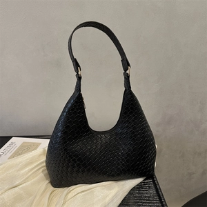 Fashion woven black leather tote bag with gold ring handle on a minimalist background