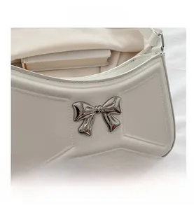 Détail du sac à bandoulière en cuir PU blanc avec nœud en métal argenté et couture géométrique