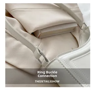 Vue détaillée de la boucle argentée et des coutures fines sur le sac en cuir blanc
