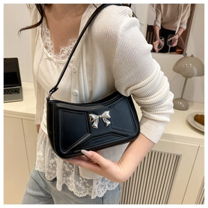 Modella indossa borsa a spalla in pelle PU nera con fiocco in metallo argento