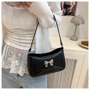 Dettaglio della borsa sottobraccio in pelle nera con fiocco argento e cuciture geometriche
