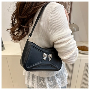 Détail d'un sac à bandoulière en cuir PU noir avec boucle en métal sur une tenue blanche