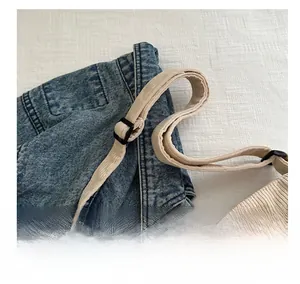 Dettaglio della borsa tote in denim blu con tracolla beige a costine e fibbia in plastica