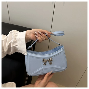 Dettaglio borsa sottobraccio celeste con fiocco in metallo argento e pelle PU liscia