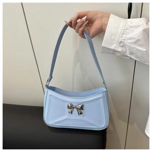 Dettaglio borsa a spalla azzurra con fiocco in metallo argento e pelle opaca