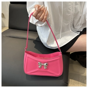 Dettaglio di una borsa sottobraccio rosa con decorazione a fiocco in metallo argento