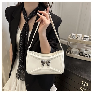 Dettaglio della borsa baguette bianca con fibbia a fiocco in metallo e trame geometriche