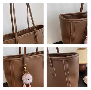 Close-up of brown faux leather tote bag with fine stitching and pink plush charm