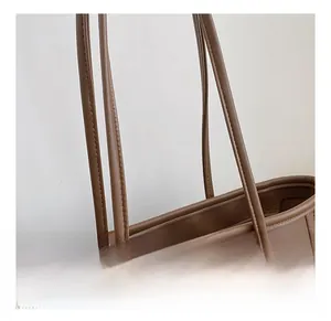 Detailed macro view of the brown leather tote bag shoulder strap with reinforced double stitching