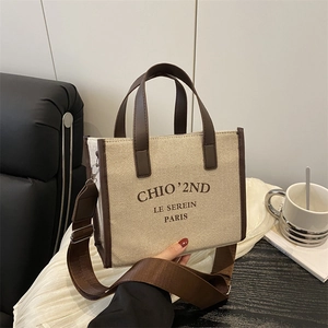 Elegant beige canvas tote bag with brown leather trim and stylish branding for women