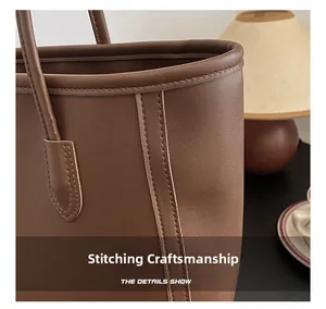 Detailed view of precise stitching on brown leather tote bag with a matte finish