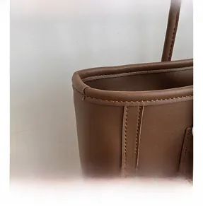 Close-up of fine leather texture and durable double stitching on the brown tote bag