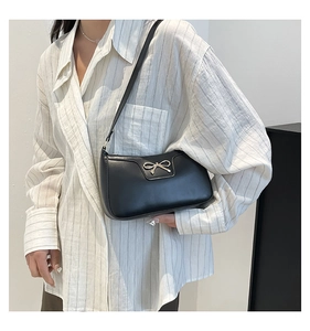 Détail du nœud argenté et texture du cuir sur le sac porté épaule noir baguette
