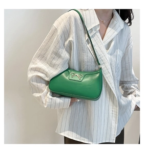 Detail of green leather underarm bag featuring a vintage golden bow metal clasp