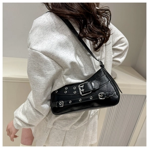Detail view of the silver buckles and metal eyelets on the black faux leather shoulder bag