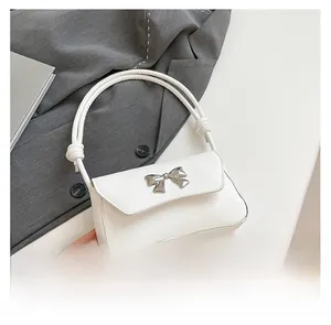 Detail of white butterfly handbag featuring knotted handle and silver metal bow ornament