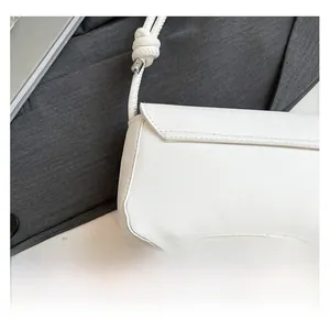 Detail of white PU leather shoulder bag featuring unique knotted strap and silver hardware