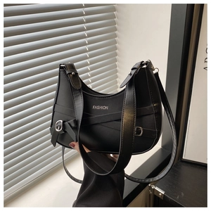 Detail of black faux leather crescent bag with silver fashion text and bow metal buckle