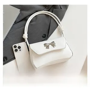 Top view of a white leather bag with a silver butterfly and smartphone for size scale