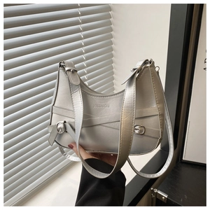 Macro detail of silver crescent shoulder bag featuring FASHION embossing and metal buckles