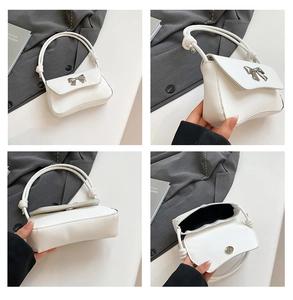 Close-up of white leather underarm bag featuring silver bow and magnetic closure details