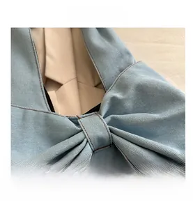 Detail of light blue denim fabric with decorative bow and premium brown double stitching