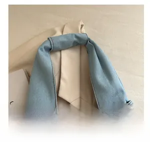 Close-up of denim handbag handle with dark brown contrast stitching detail
