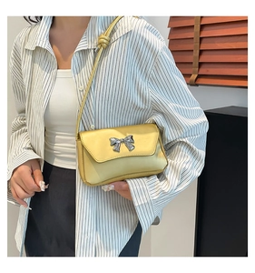 Detail of yellow satin shoulder bag with silver metal bow and knotted strap design