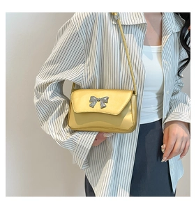 Close-up of yellow baguette bag with silver bow buckle on model shoulder