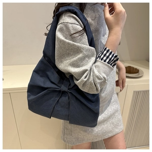 Close-up of deep blue denim tote bag with oversized bow detail in minimalist interior
