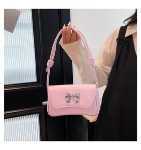 Detail of pink rectangular crossbody bag featuring a silver metal bow buckle clasp