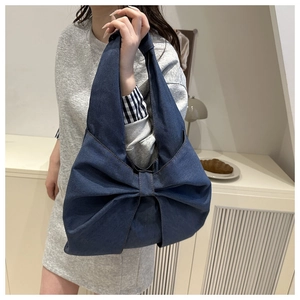 Detailed close-up of large denim bow design on a stylish navy blue tote bag