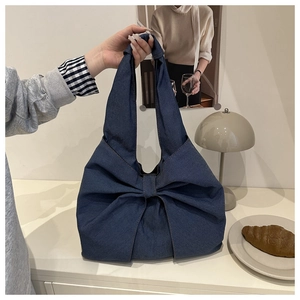 Detailed close-up of dark blue denim tote bag featuring a large decorative bow design