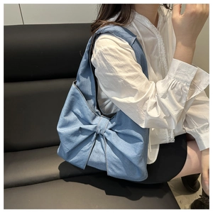 Close-up of blue denim tote bag featuring a large bow detail and spacious design